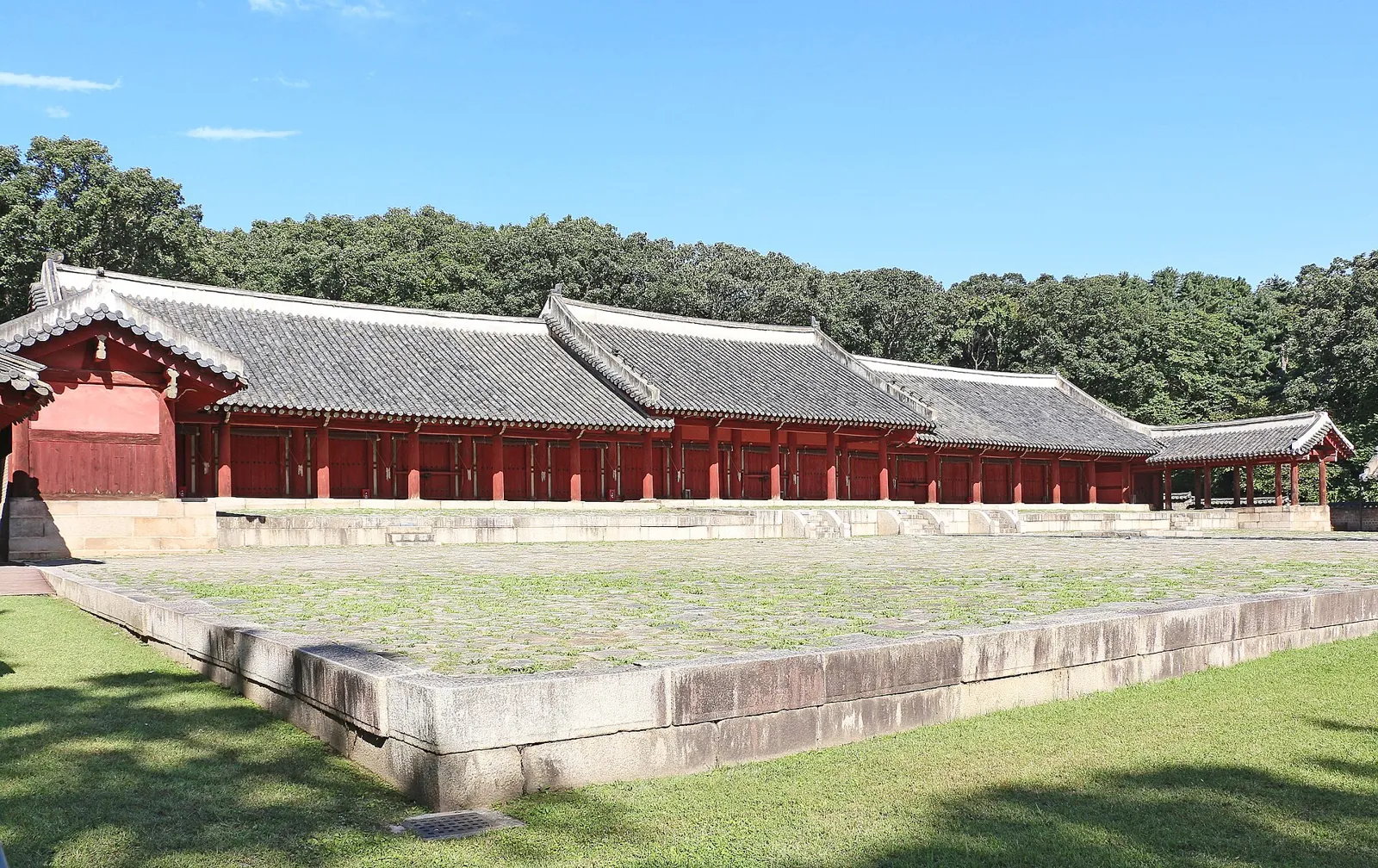 Long red-walled hall Yeongnyeongjeon at Jongmyo Shrine behind a grassy courtyard