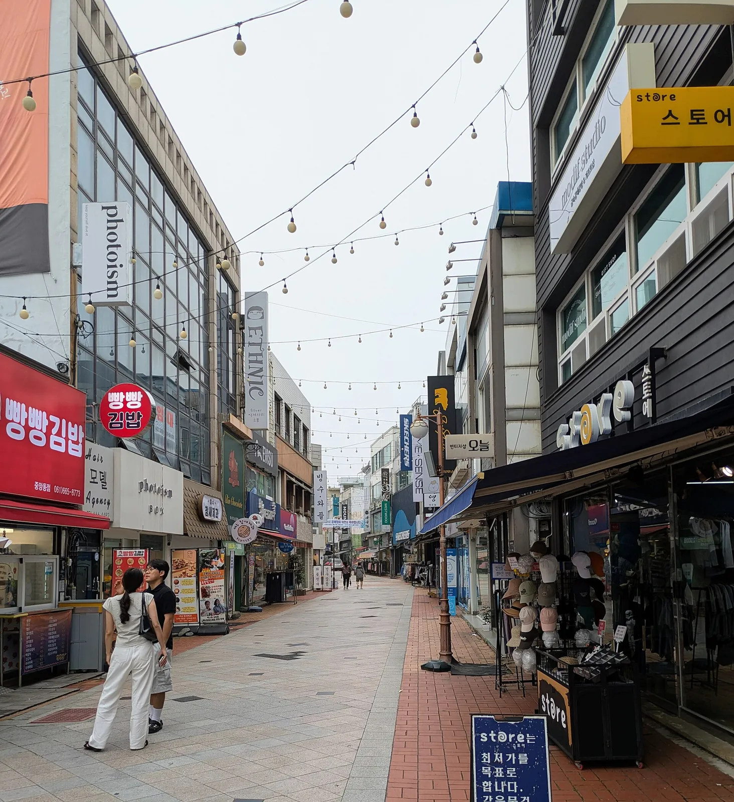 Pedestrian shopping street Jinnamsangga-gil in Yeosu with shops and a person walking